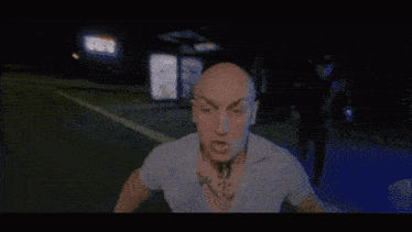 a bald man with a tattoo on his chest is holding a bottle that says ' vodka ' on it