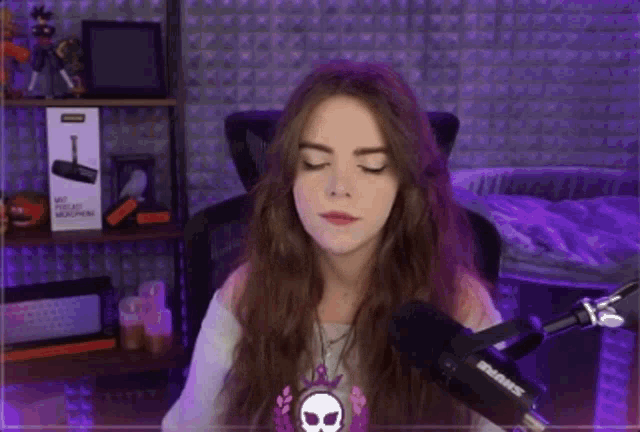 a woman is sitting in front of a microphone and blowing a kiss .