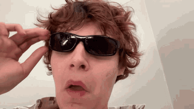 a young man wearing sunglasses makes a face