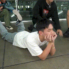 a man in a white shirt is laying on the ground with his hands on his chin