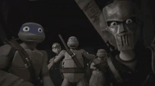 a group of teenage mutant ninja turtles are standing next to each other in the dark .