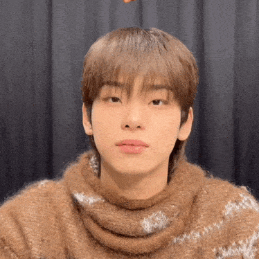 a close up of a person wearing a brown sweater and scarf