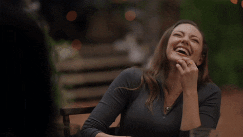 a woman laughs while sitting at a table with a man