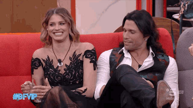 a man and a woman are sitting on a red couch with the hashtag #gfvip on the bottom