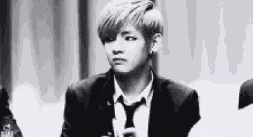 a black and white photo of a man in a suit and tie holding a microphone .