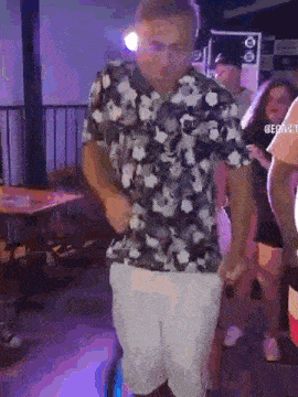 a man in a floral shirt is dancing in a club