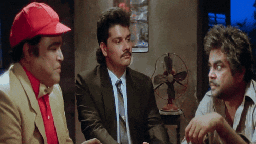 a man in a red hat talks to two other men
