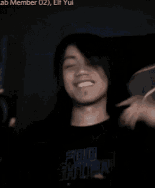 a man in a black shirt is smiling and looking at his phone