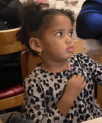 a little girl wearing a leopard print shirt looks to the side