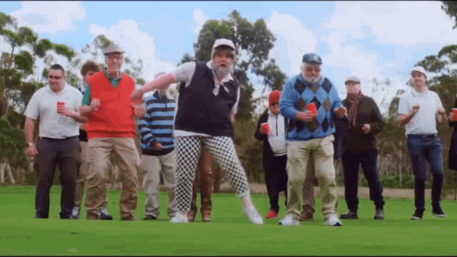 a group of men are standing on a golf course and one of them is dancing