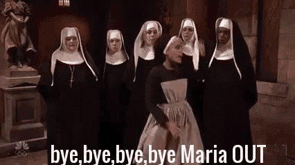 a group of nuns are standing next to each other in a church and talking to each other .