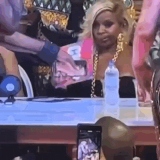 a woman is sitting at a table taking a picture of herself with her cell phone .