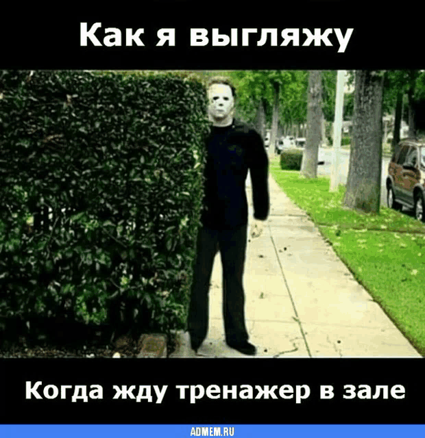 a man in a mask is standing in front of a hedge on a sidewalk