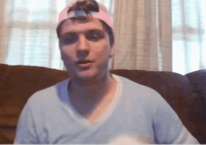 a man wearing a pink hat is sitting on a couch .