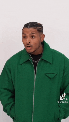 a man in a green jacket is standing in front of a white background .