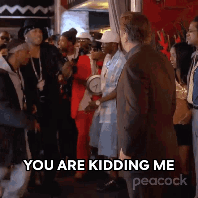 a man in a suit stands in front of a crowd of people and says " you are kidding me " .