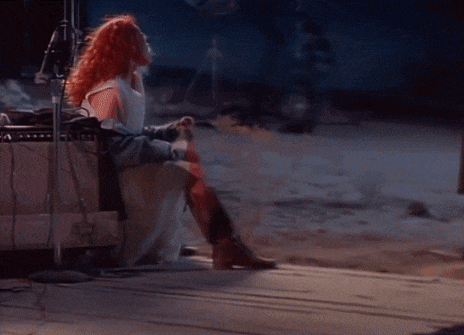 a woman with red hair is sitting in front of an amplifier with the letter s on the front