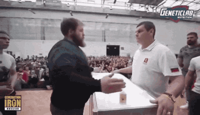 a man shakes hands with another man in front of a crowd that says geneticlab