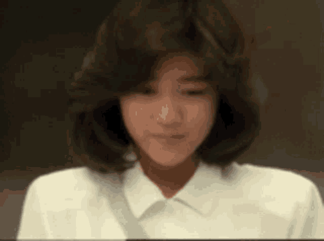 a woman with short hair is wearing a white shirt .