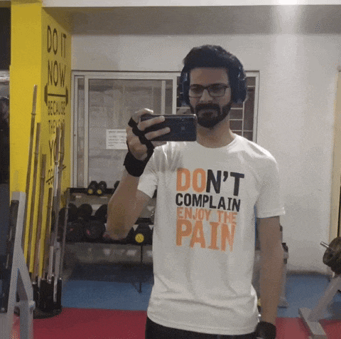 a man wearing a shirt that says " do n't complain enjoy the pain " takes a picture of himself