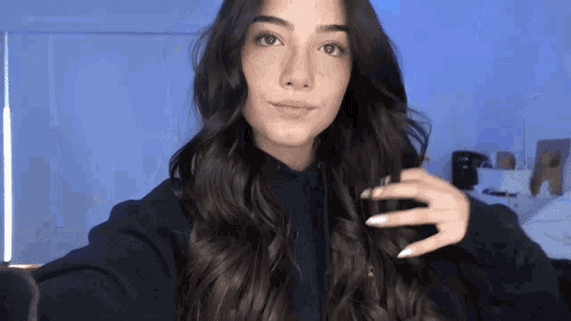 a woman with long hair is taking a selfie with her hand in her hair
