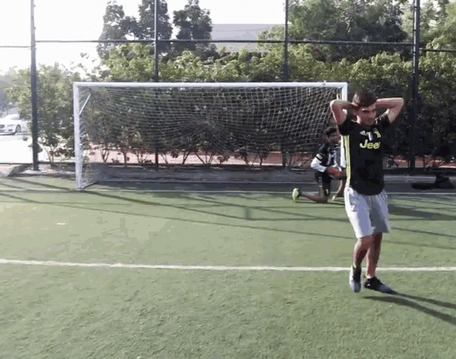 a man wearing a jeep shirt is standing on a soccer field