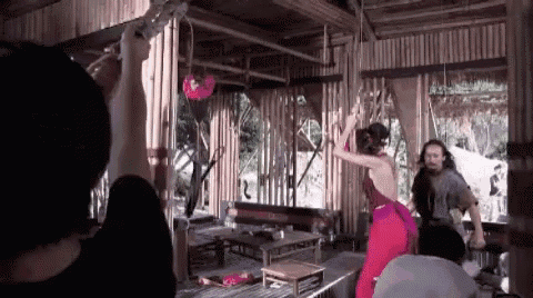 a man is taking a picture of a woman in a red dress in a hut .