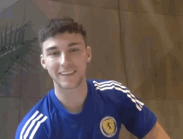 a man wearing a blue shirt with the scotland flag on it smiles