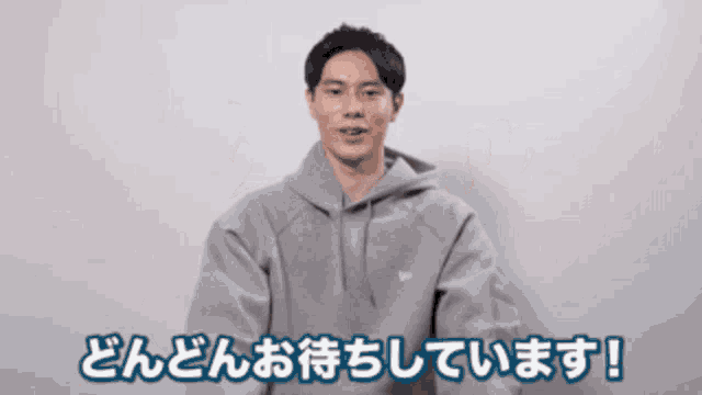 a man wearing a grey hoodie with chinese writing on the bottom