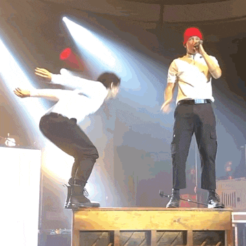 a man in a red hat is singing into a microphone on a stage