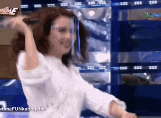 a woman wearing a face shield and glasses is dancing on a stage .