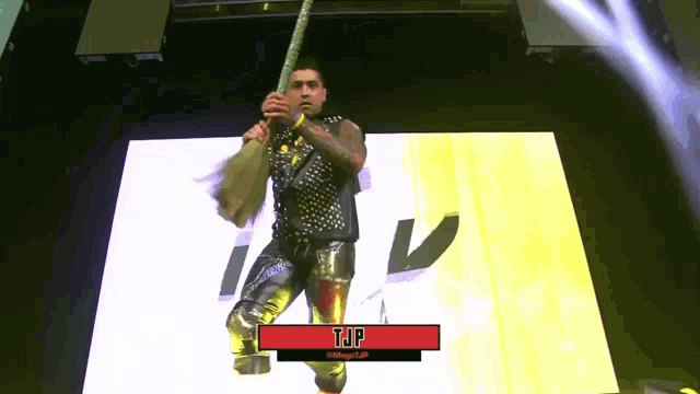 a wrestler named tjp is holding a rope on a stage