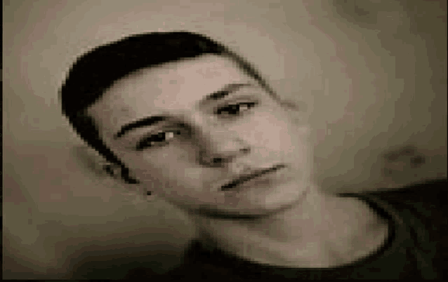 a young man with a shaved head is looking at the camera .