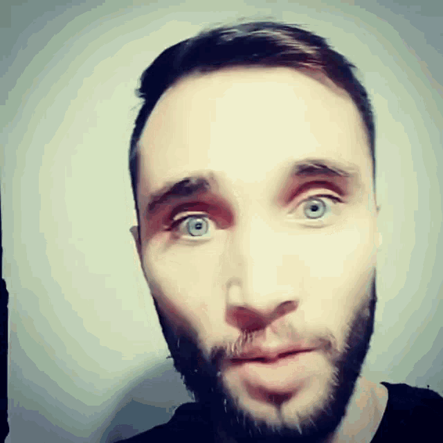 a man with a beard and blue eyes makes a surprised face