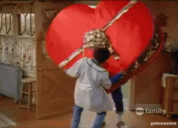 a couple of people holding a large red heart with abc family written on the bottom right