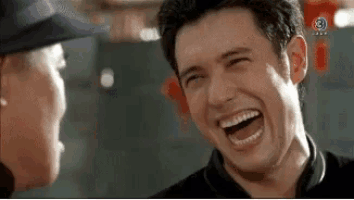 a man is laughing while talking to another man in a blurry photo .