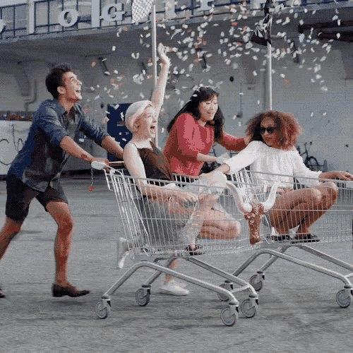a group of people pushing shopping carts with confetti falling in the background