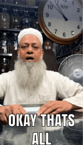 a man with a beard is sitting at a table with okay thats all written on it