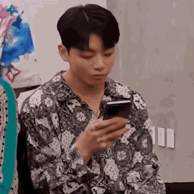 a man is sitting in a chair looking at his phone .