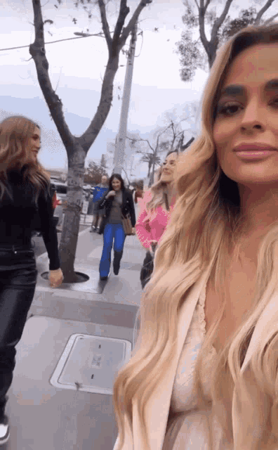 a group of women are walking down a sidewalk with a manhole cover in the background
