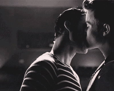 a black and white photo of two men kissing .