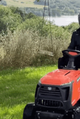 a man is riding a red lawn mower in a field