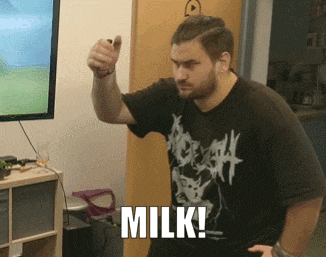 a man wearing a black shirt that says death is standing in front of a television and says milk