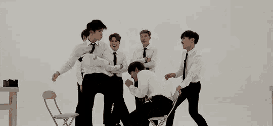 a group of men in ties and suspenders are dancing in a room .