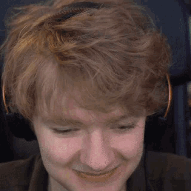 a young man wearing headphones is smiling while sitting in a chair .