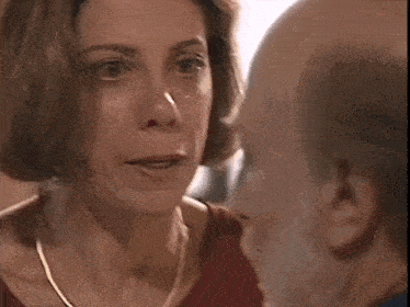 a woman and a bald man are looking at each other and the woman is making a funny face .