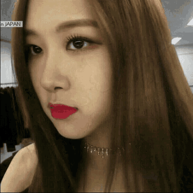 a close up of a woman 's face with a choker and red lipstick