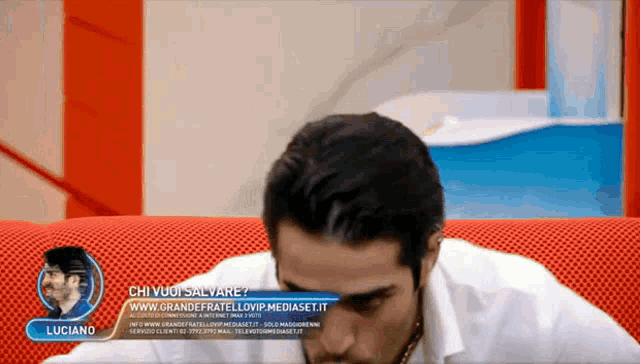 a man sits on a red couch with a banner that says " luciano "