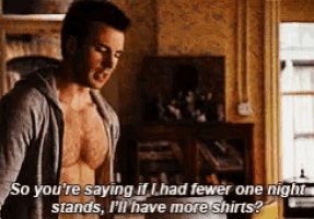 a shirtless man is talking to another shirtless man while standing in a living room .