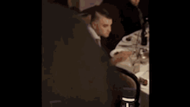 a man in a white shirt and tie is sitting at a table in a restaurant .